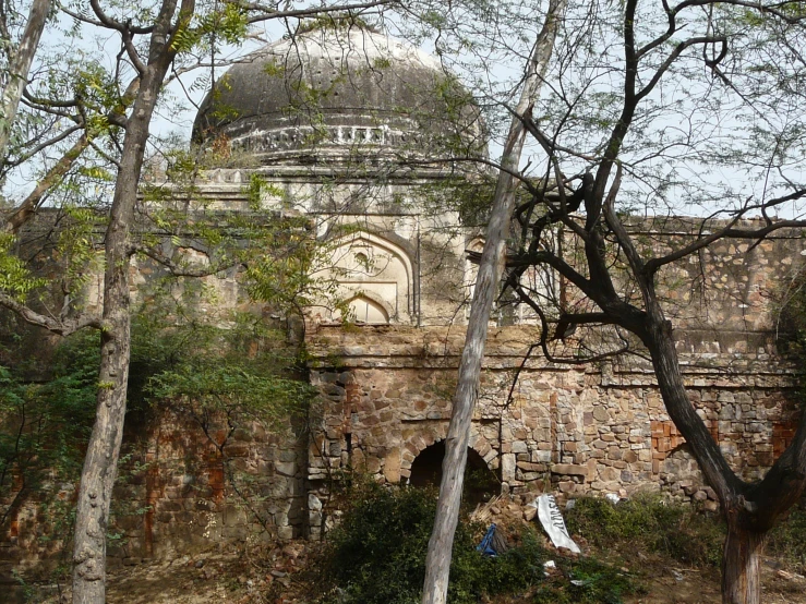 a large ancient building behind a fence and tree