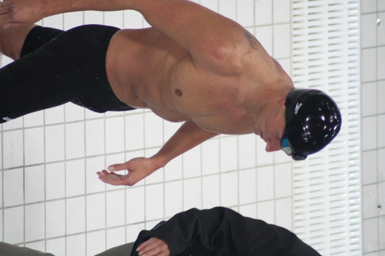 a man without a shirt is walking along with a wet suit on