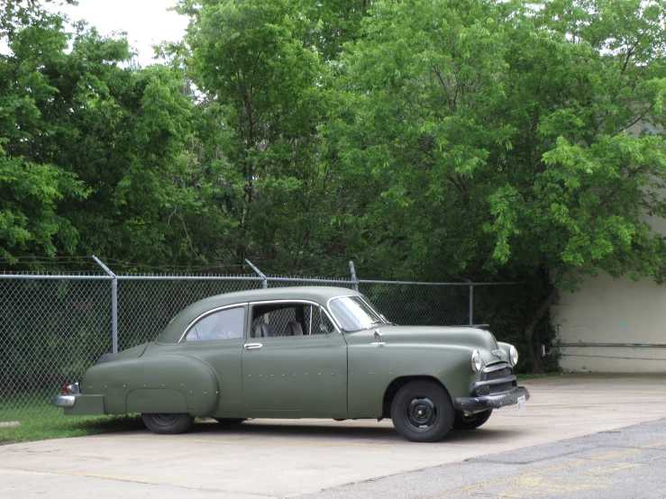 a green car in front of a fence and trees
