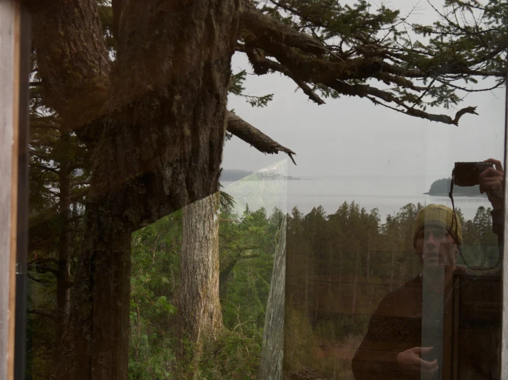 a man is taking a po through the reflection of a tree