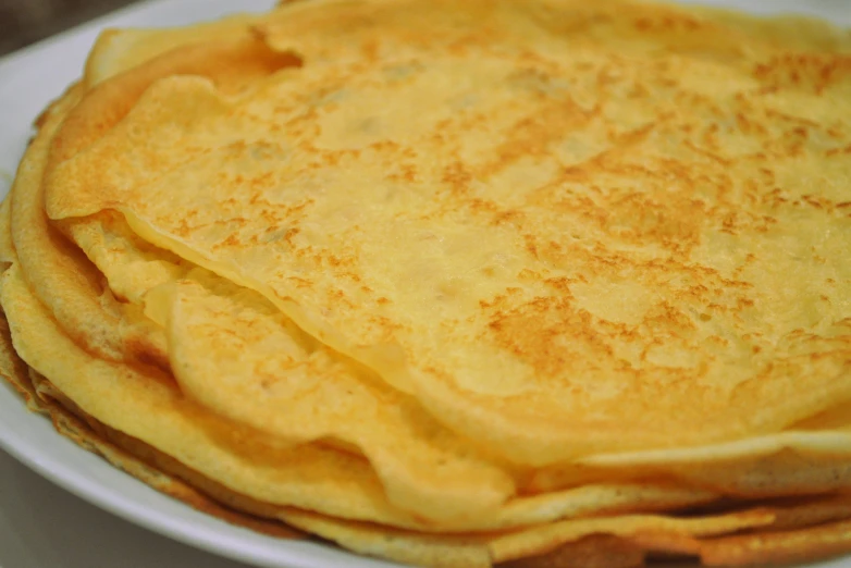 a white plate holding some pancakes with powdered sugar