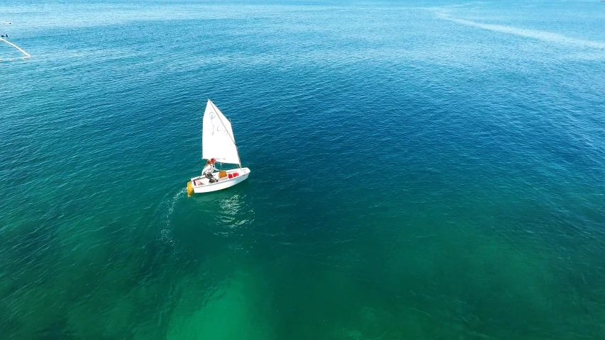 a man riding a sailboat on top of blue water