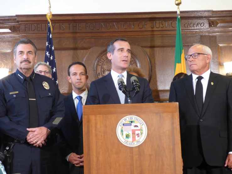 some people and an officer in suits at a podium