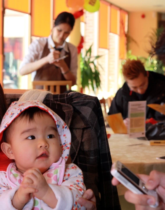 a woman holding a baby in her lap and two men with cell phones