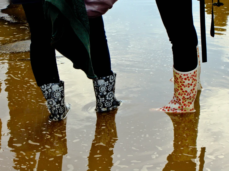 two people with rain boots on standing in dles