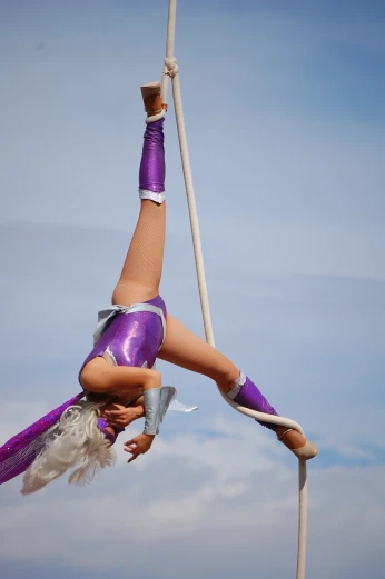 female aerial acrobatic entertainer demonstrating ss on top of pole