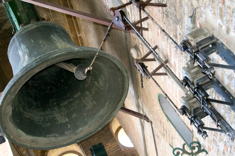 two old bells are hanging from chains next to a wall