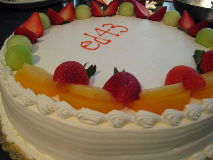 the cake is decorated with fruit and topped with a happy ecat on top