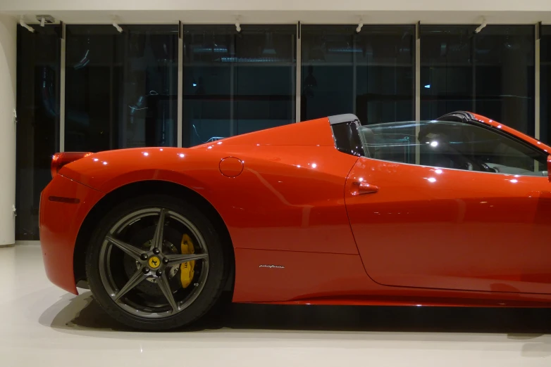 a red sports car on display with glass walls behind it