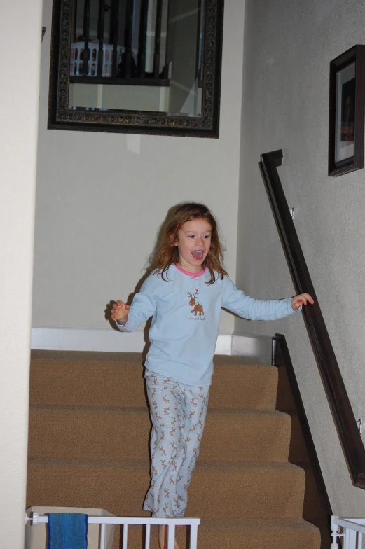 a girl in a pajamas is walking down a staircase