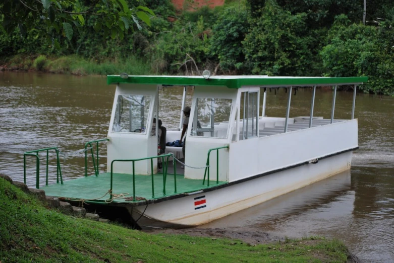 a white boat is on the water and has green railings