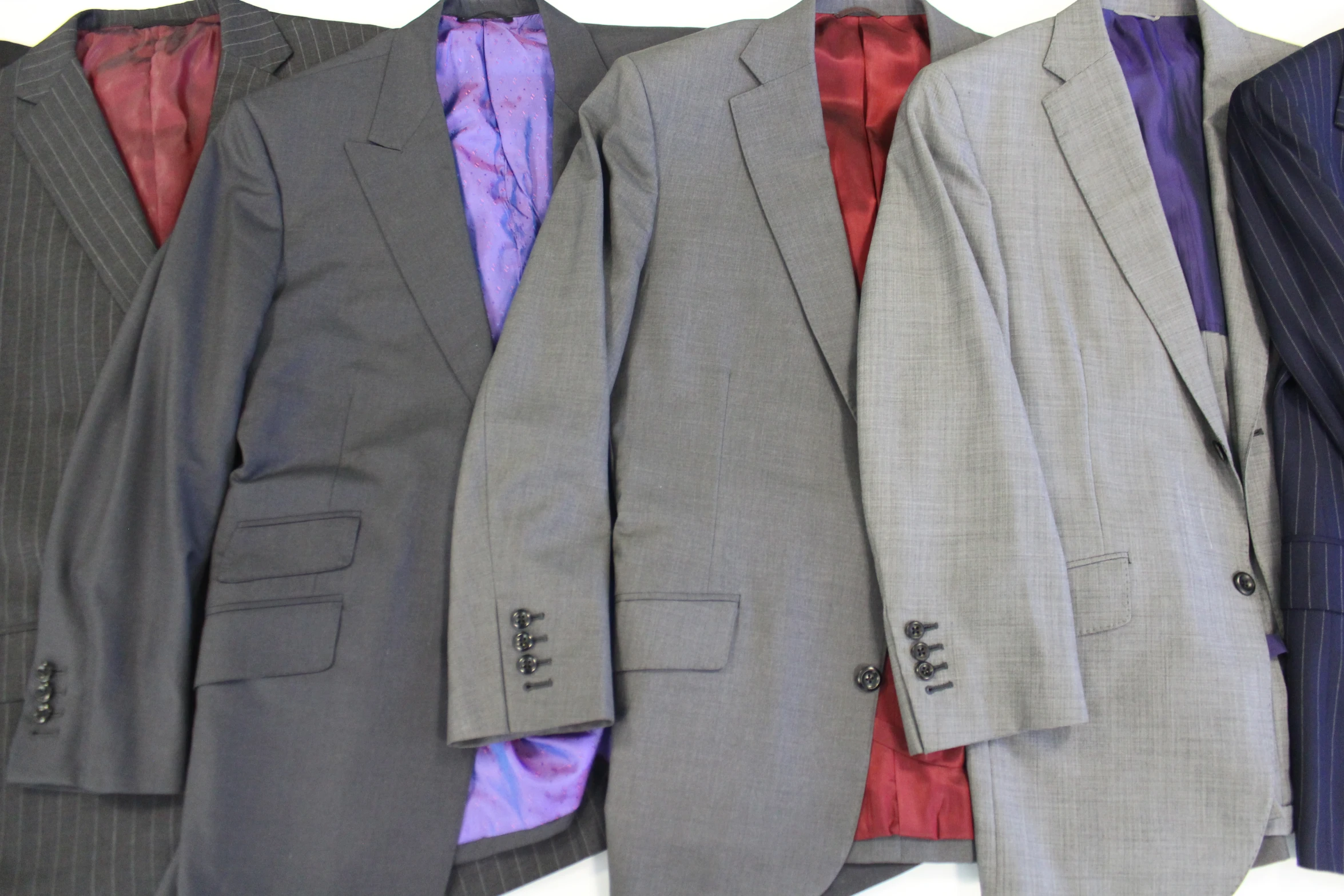 a number of suits hanging up on a wall