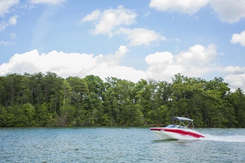 the red and white boat is driving down the water