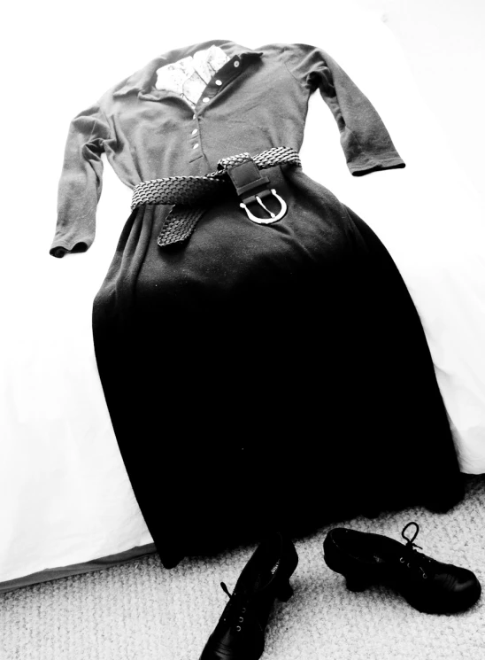 black and white pograph of dress and shoes laying on a bed