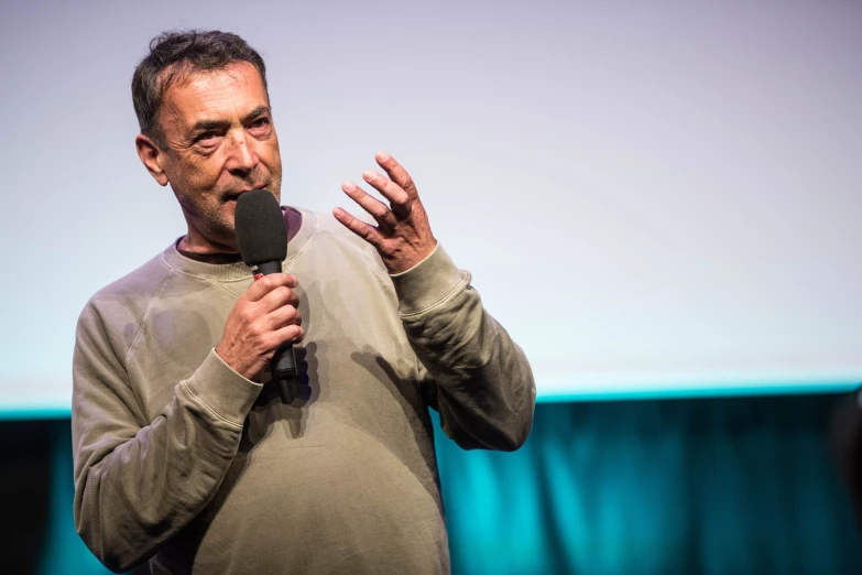 man speaking at a meeting holding up a microphone