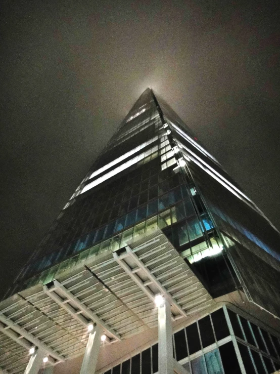 a very tall building is lit up on a cloudy night