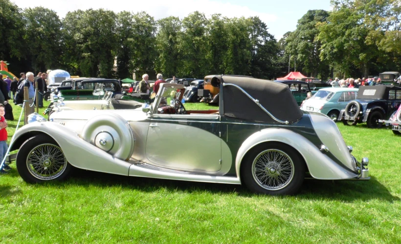 antique convertible automobile in a grassy area with people around