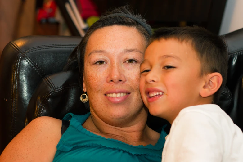 a woman smiling while holding a small boy