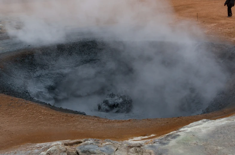 steam is spewing out of the ground in a small crater