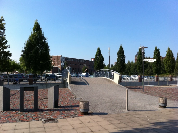 skateboarders ride their boards along a walkway between a fence and benches