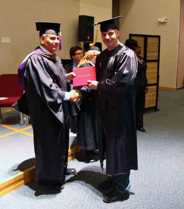 two men standing next to each other in graduation robes