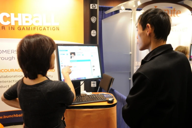 a man and woman viewing a computer display in a convention