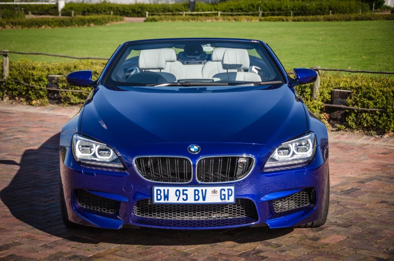 a blue convertible car is parked outside on a brick surface