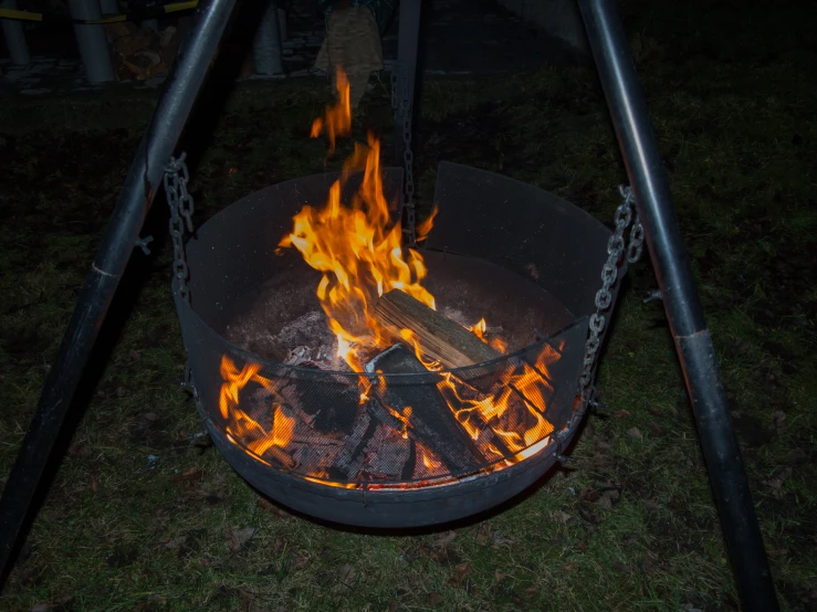 a round fire pit is lit with flames and logs