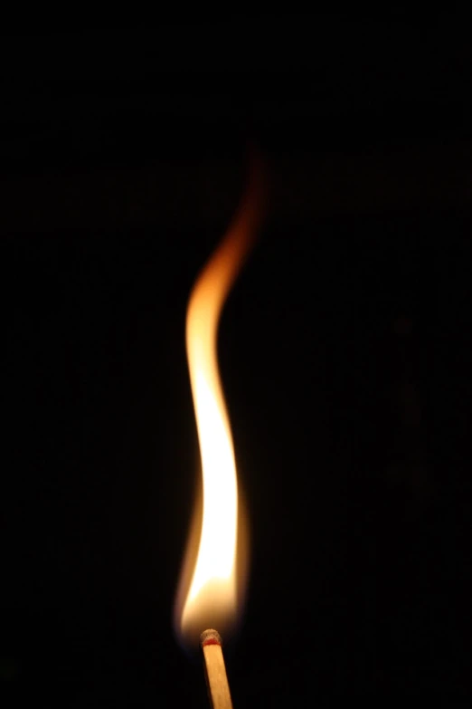 a lit matchstick on black background with small matches