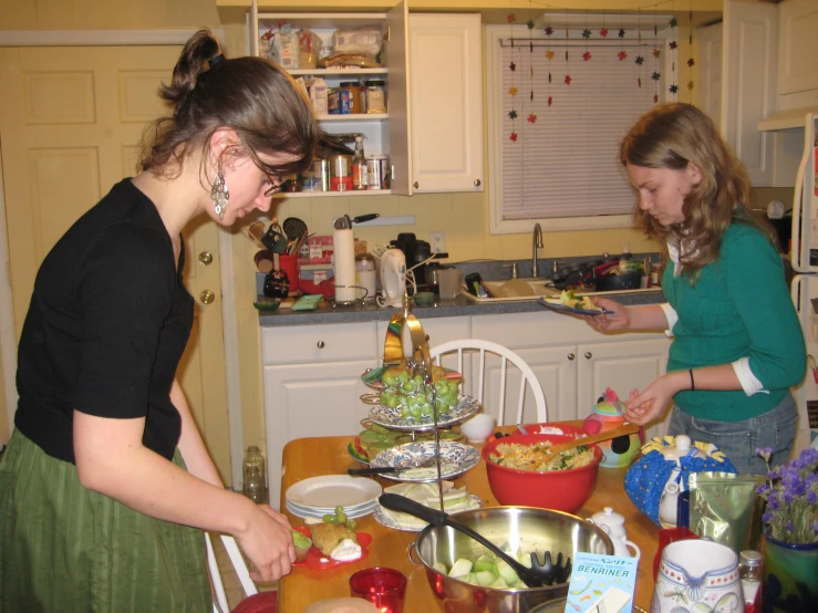 the lady are cooking at their kitchen table together