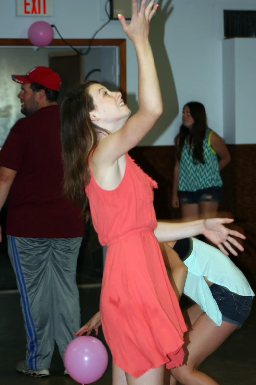 a girl in red playing with some colorful balloons