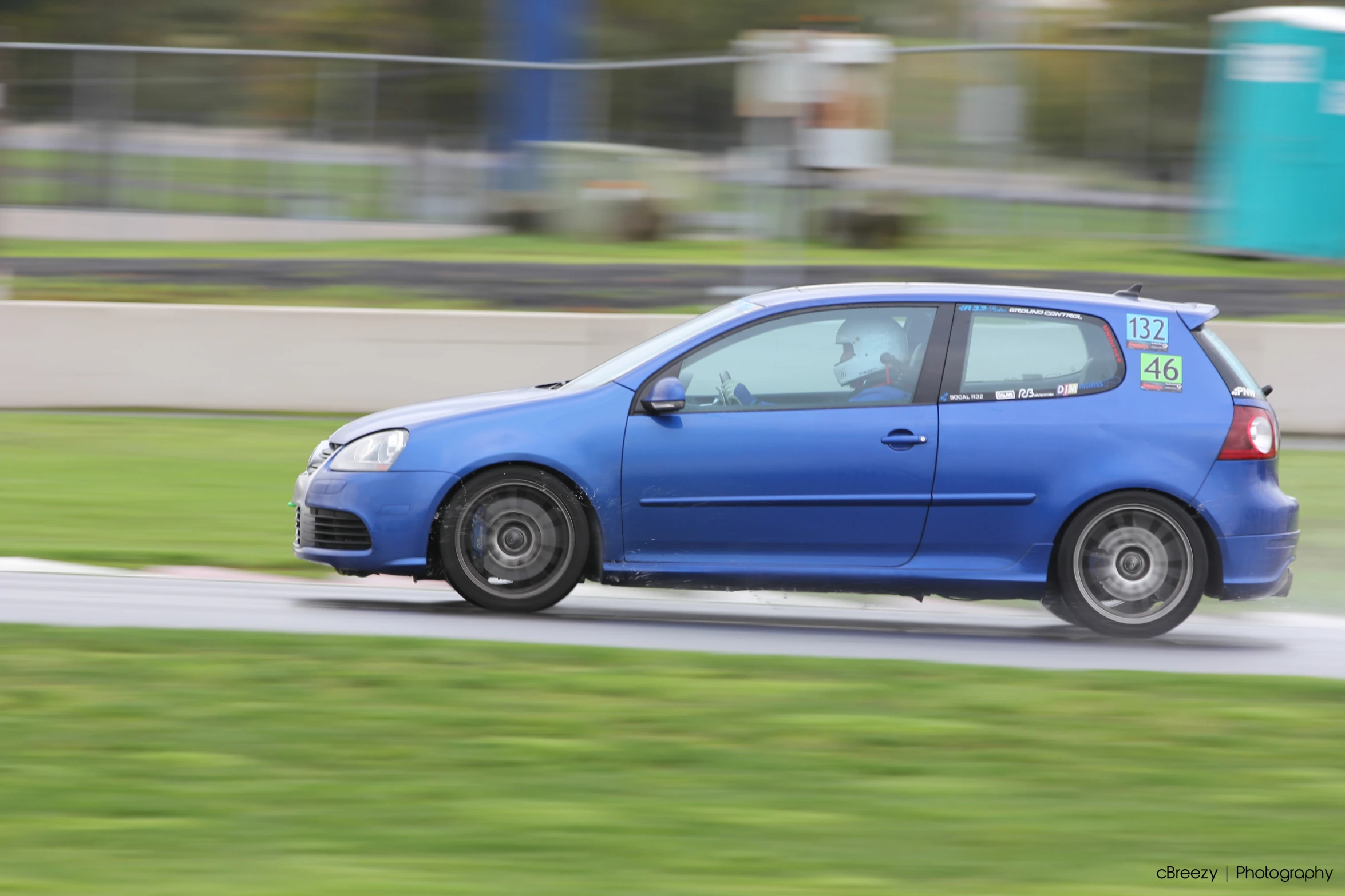 a blue car driving around a track on a sunny day