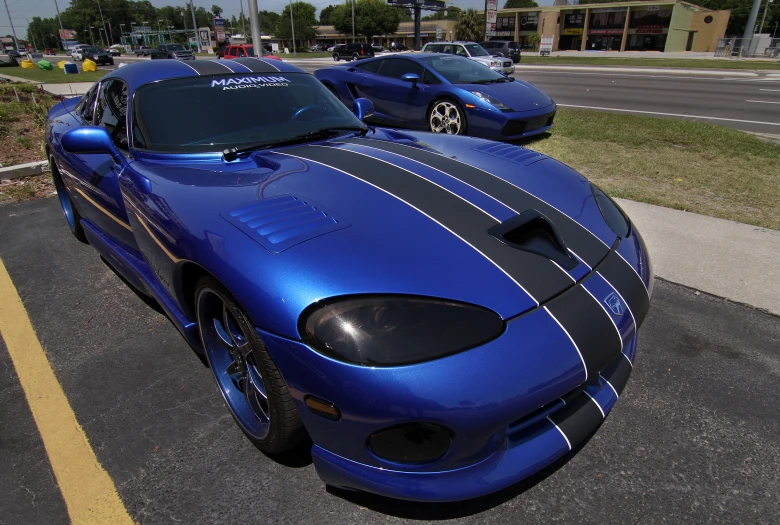 two blue sports cars are lined up in a parking lot