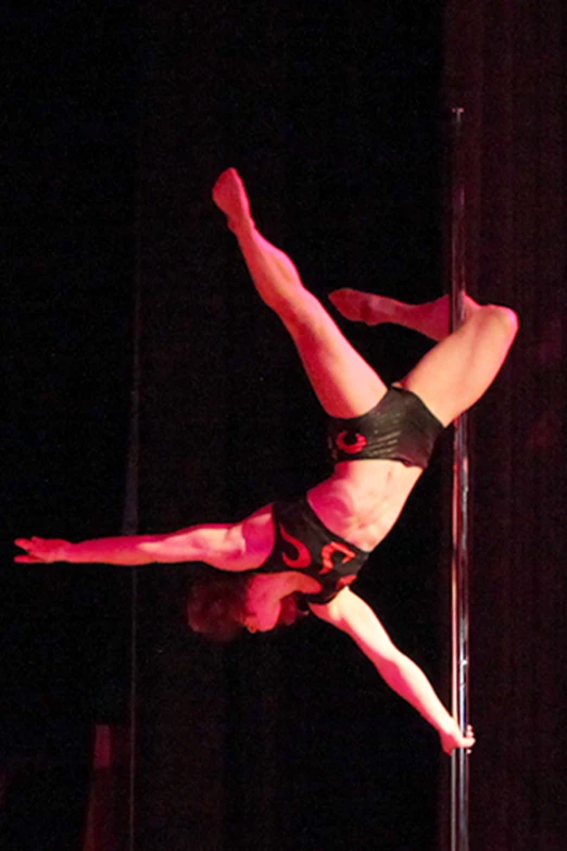 a man in a black shirt is doing pole dancing