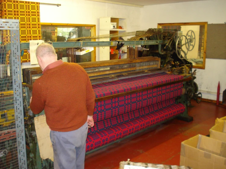 an older man working on a weaving machine