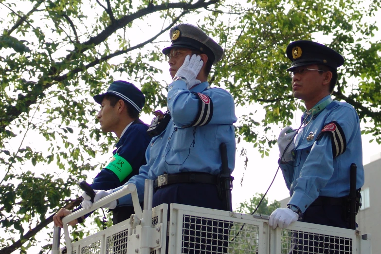 four police officers stand in the shade of trees