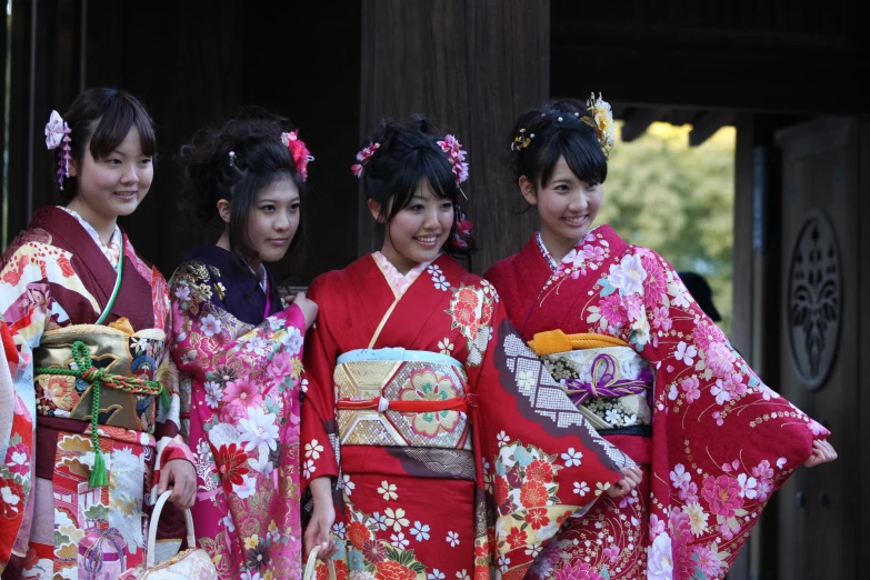 four girls dressed in kimonos are standing side by side