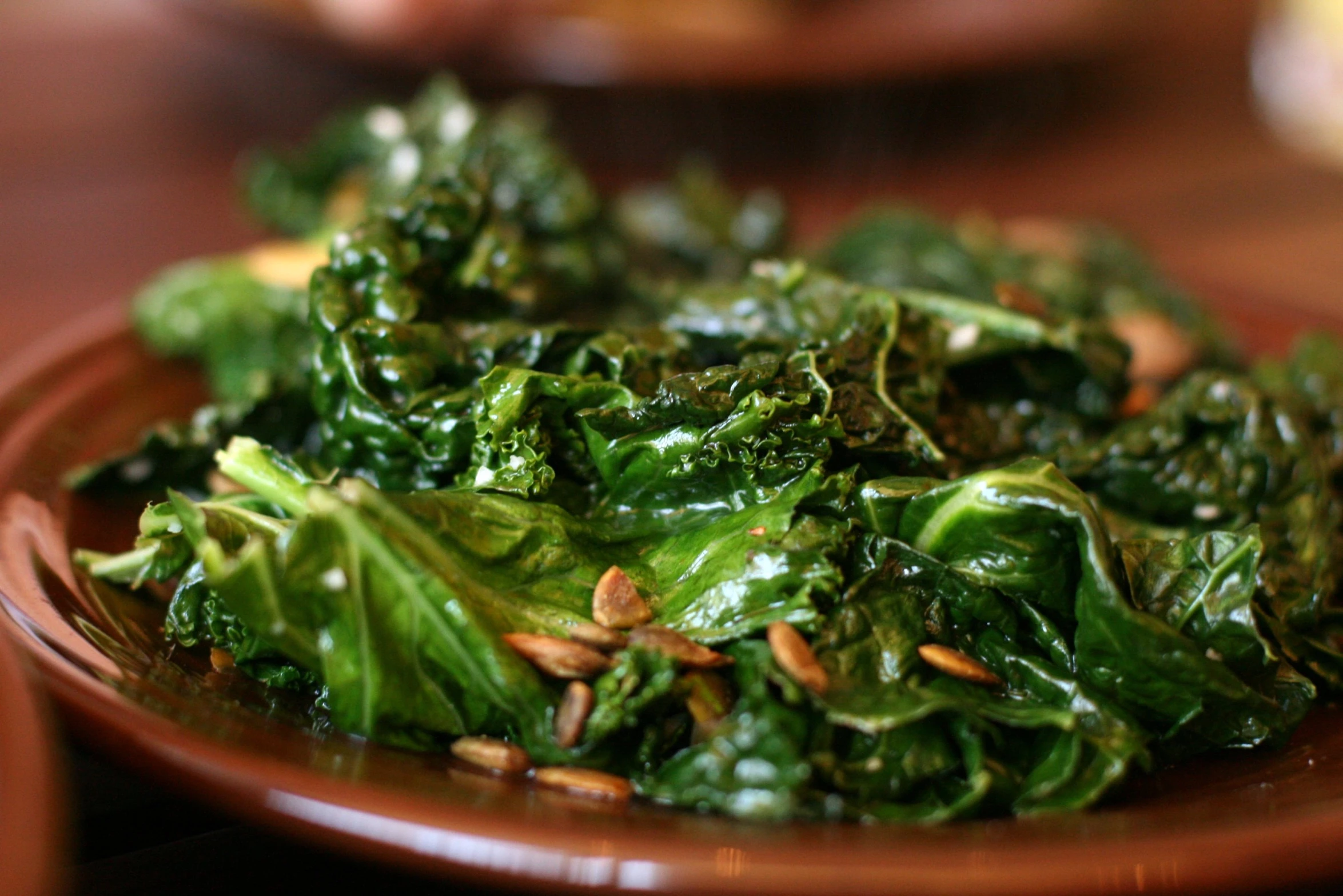 green leafy vegetables are on a plate and placed in the table