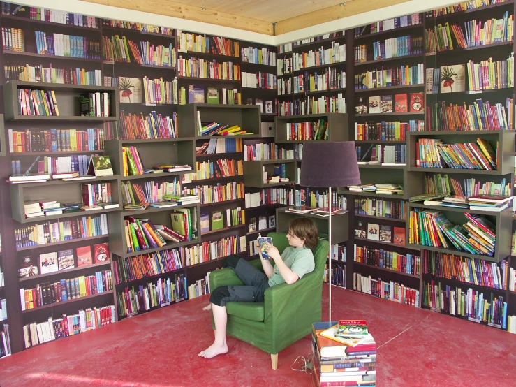 man sitting in a chair in front of a room filled with books