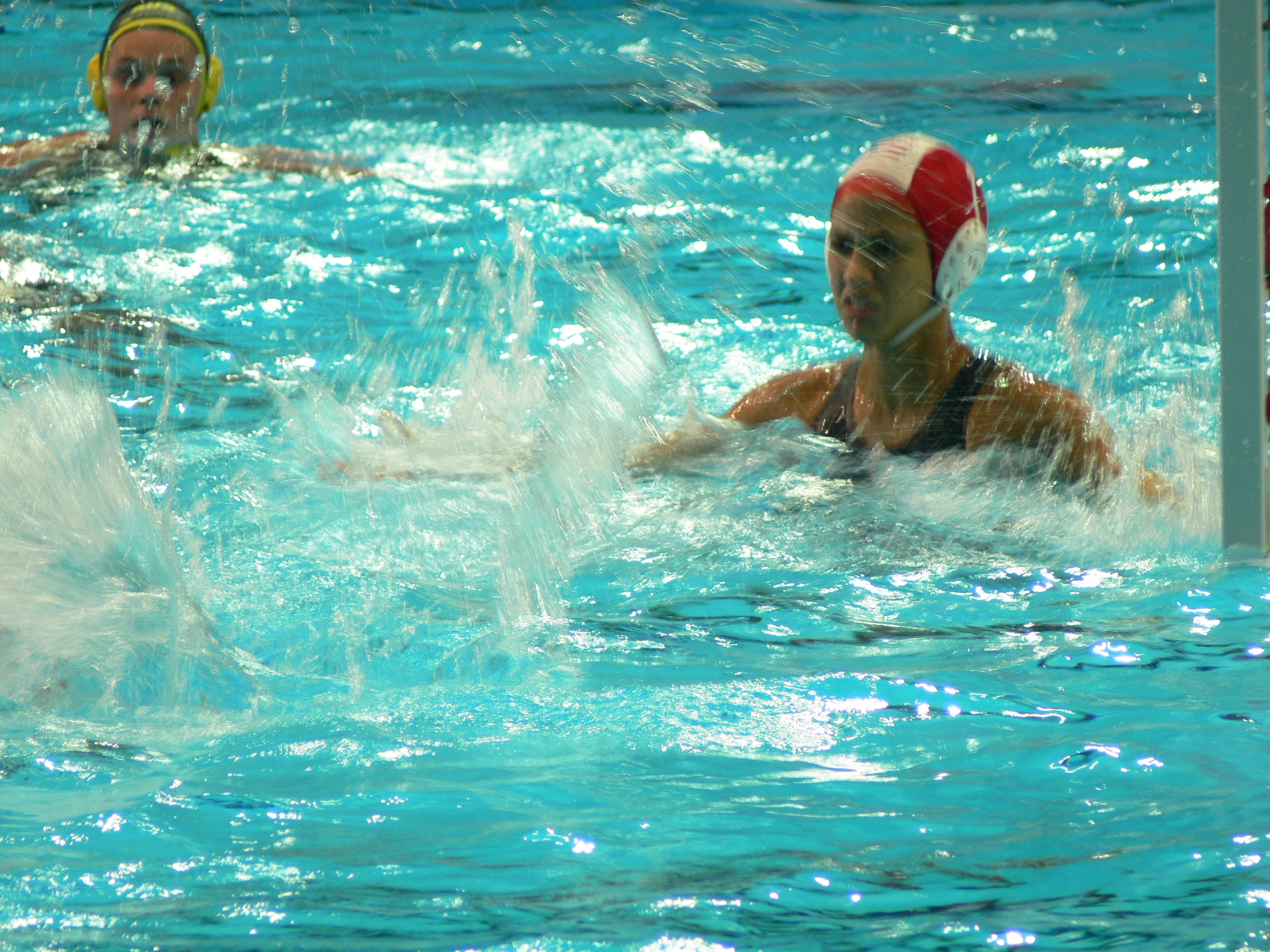 two men in a pool with water polo caps