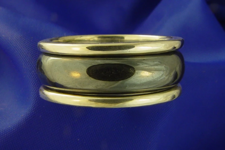 a silver and gold colored ring sitting on top of blue silk