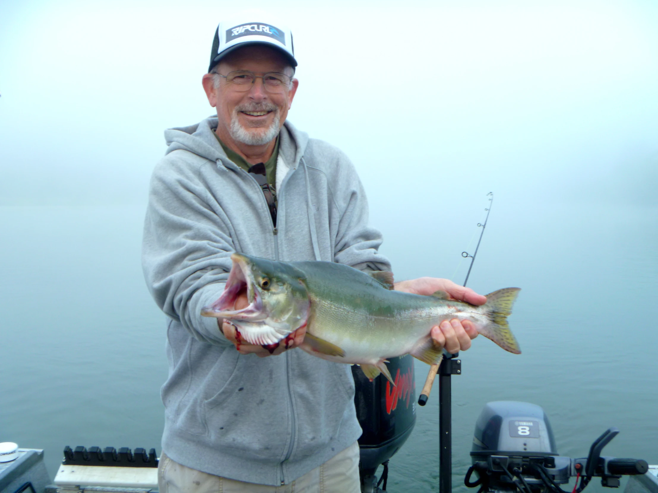 a man in a gray jacket is holding a big fish