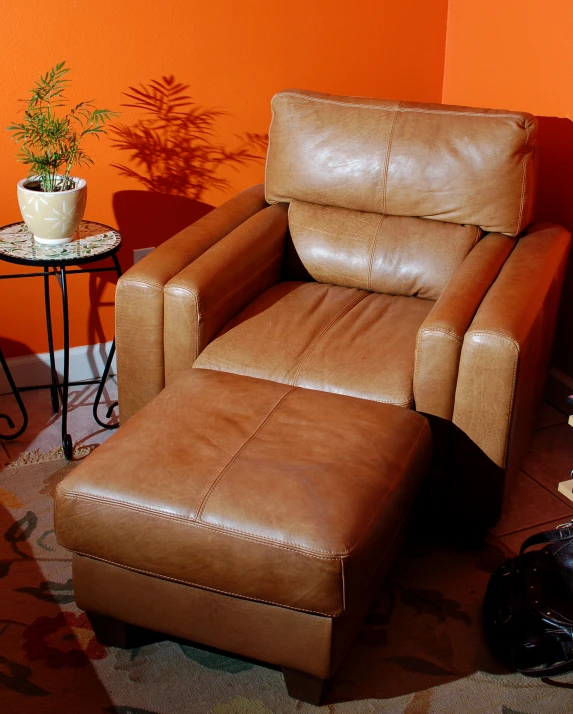 a room with orange walls and a tan recliner