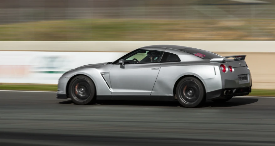 the silver sports car is driving down the road