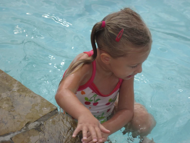 a  plays in a pool with her hands close to the water