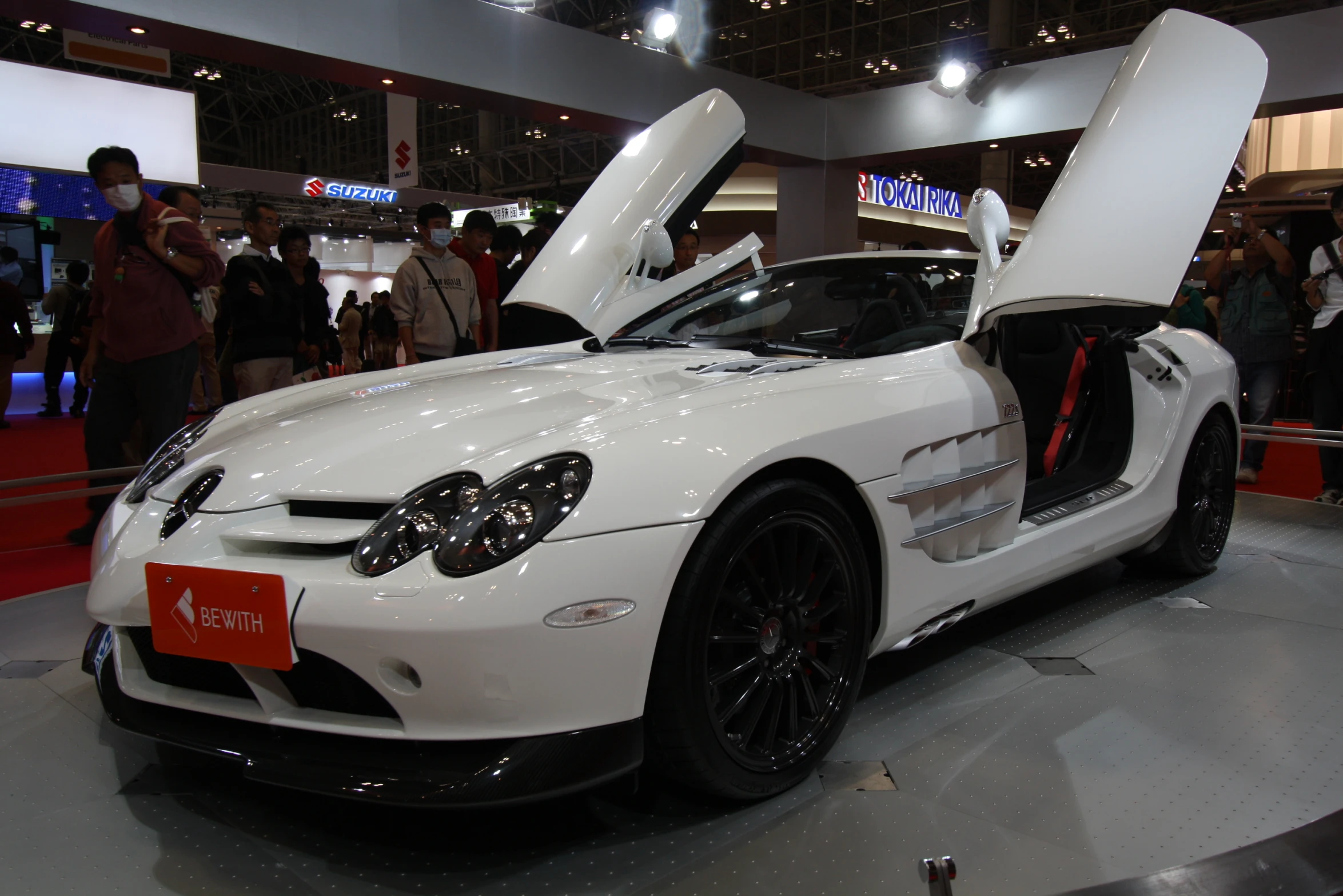 a white sports car with it's trunk open and people around