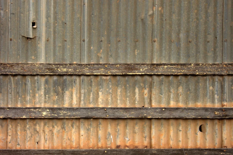 three old rusted metal rails against a brown rusty wall