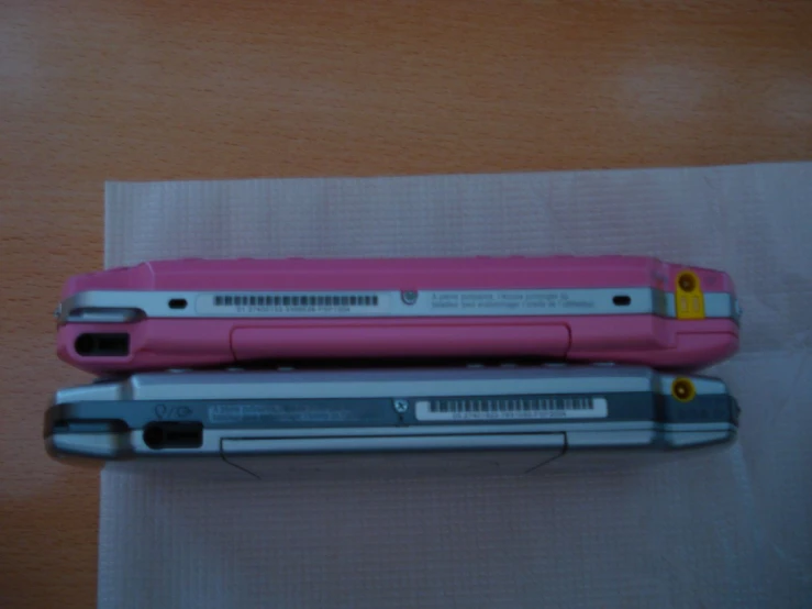 two pink and silver laptops sitting on a piece of cloth