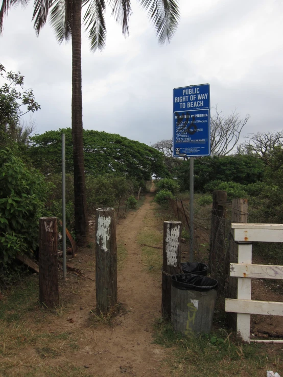 a blue sign is next to an abandoned fence