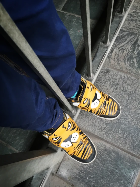 a person in blue pants wearing yellow tiger shoes